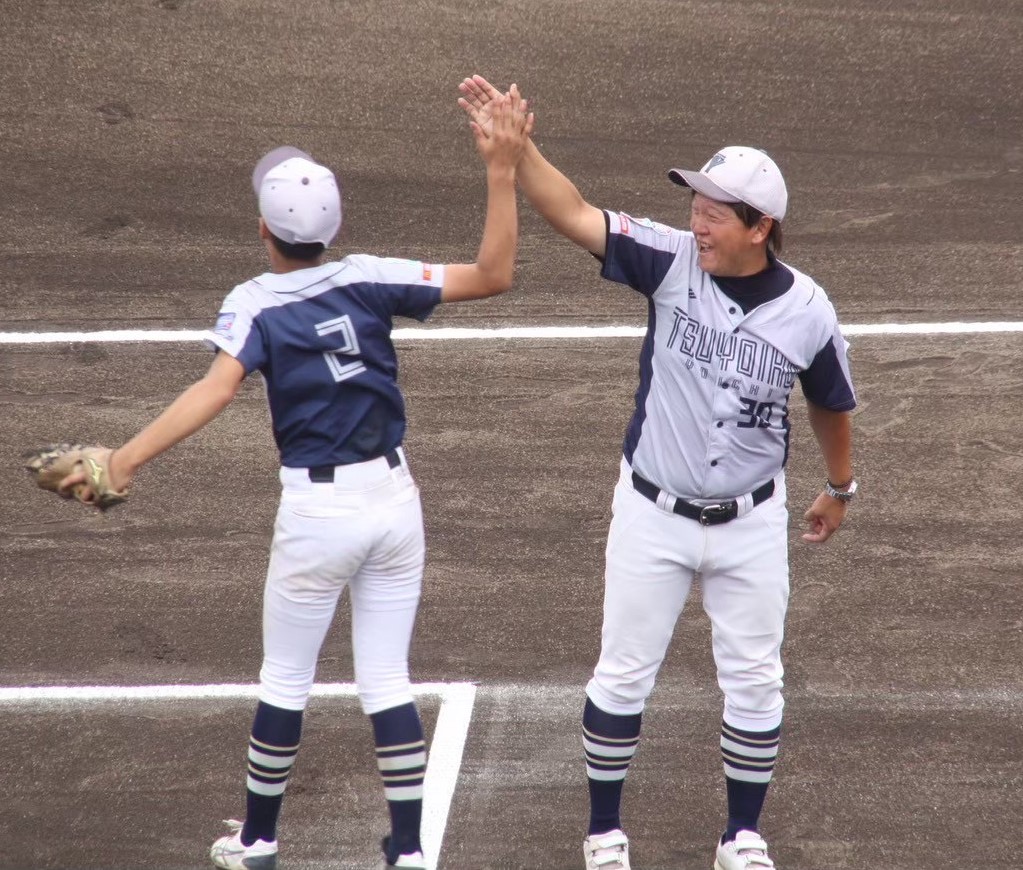 上枝監督とハイタッチする(写真・余市強い子野球スポーツ少年団提供)
